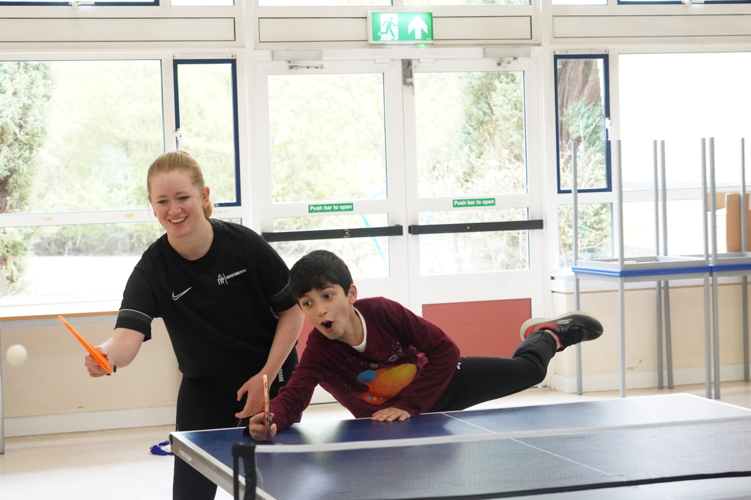 Support services at Forever Young People with a boy playing ping pong with an adult beside him