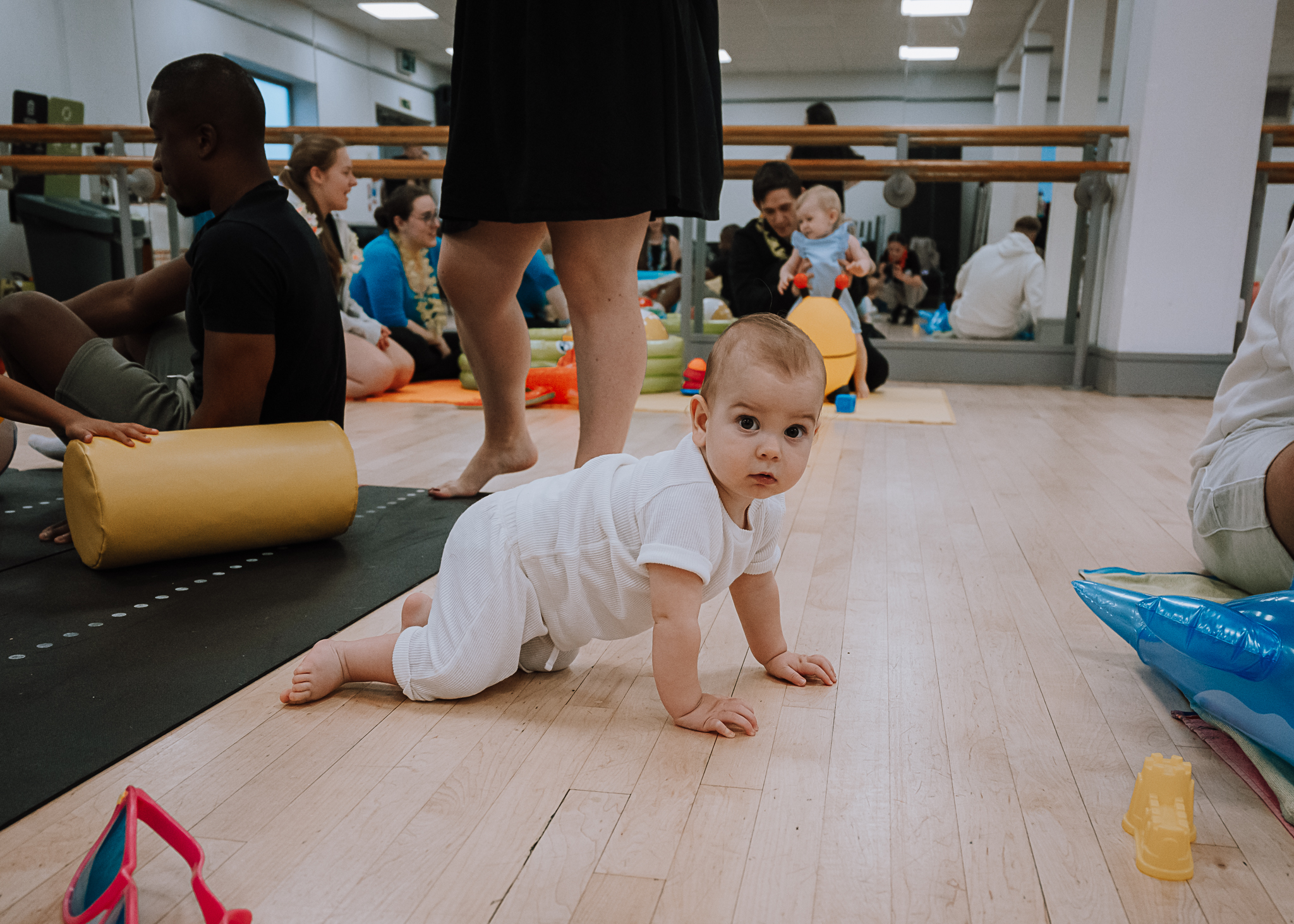 Young baby crawling at the Dots mum and baby class run by Forever Young People with a young toddler crawling