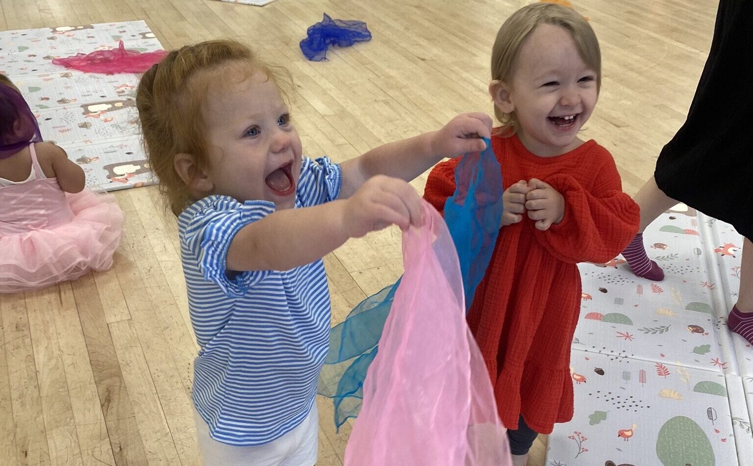 Dots mum and baby fitness class showing two children smiling and laughing